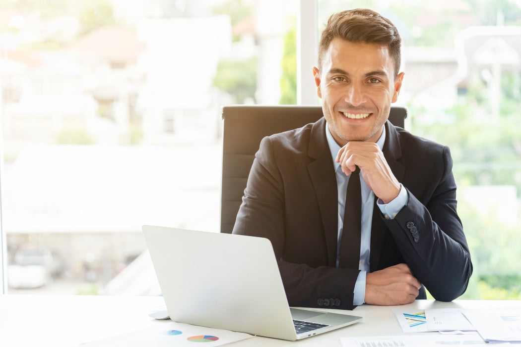 Business man posing at a desk with his laptop