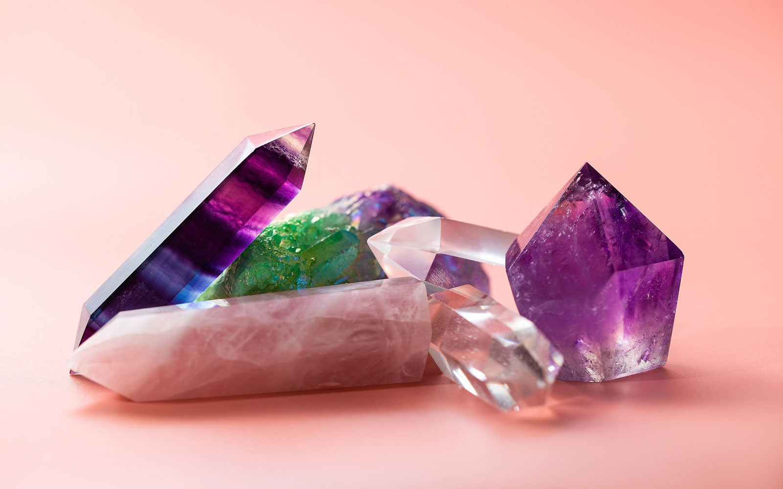 Collection of colorful healing crystals on pink background
