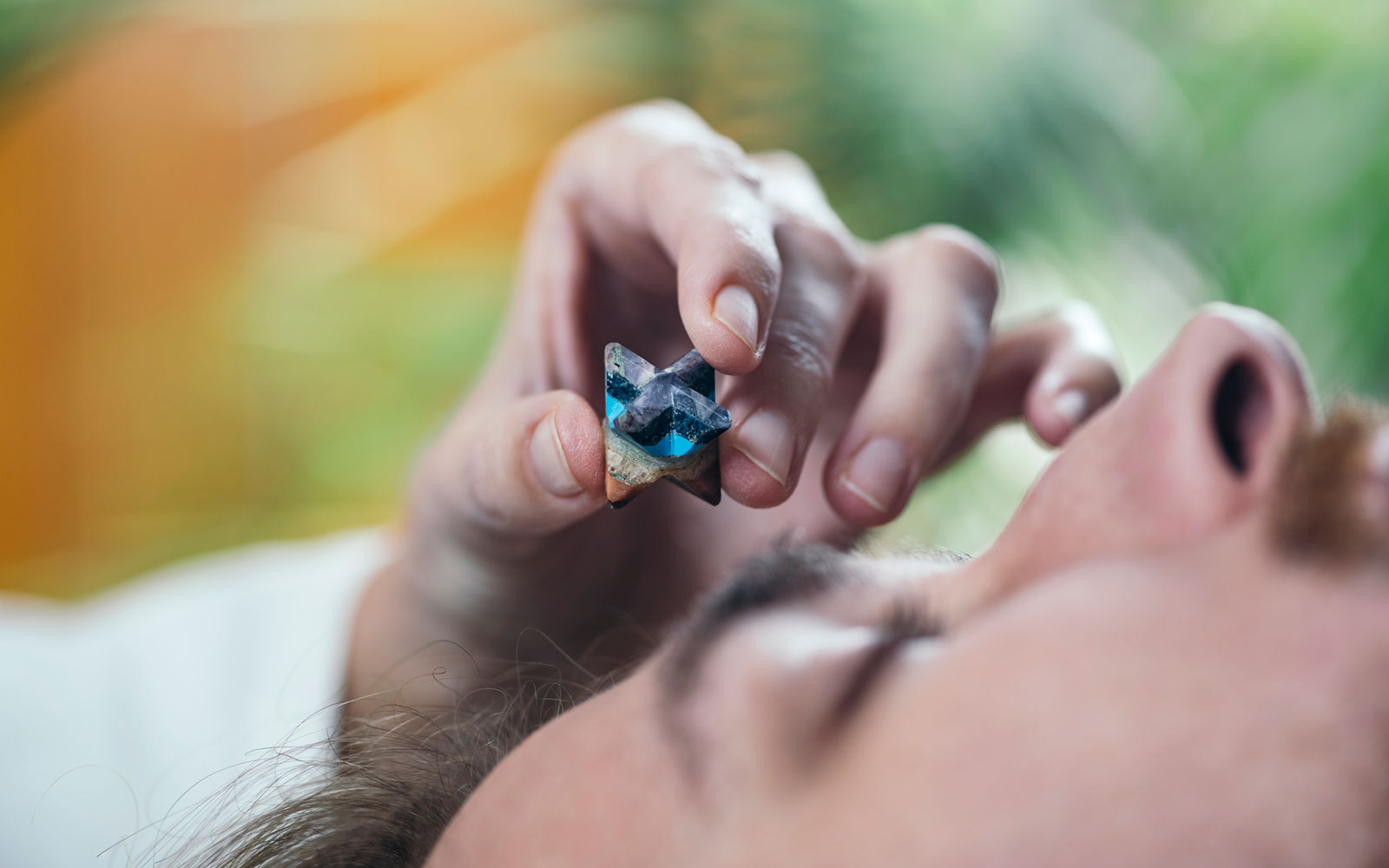 Holding a healing crystal over the third eye chakra