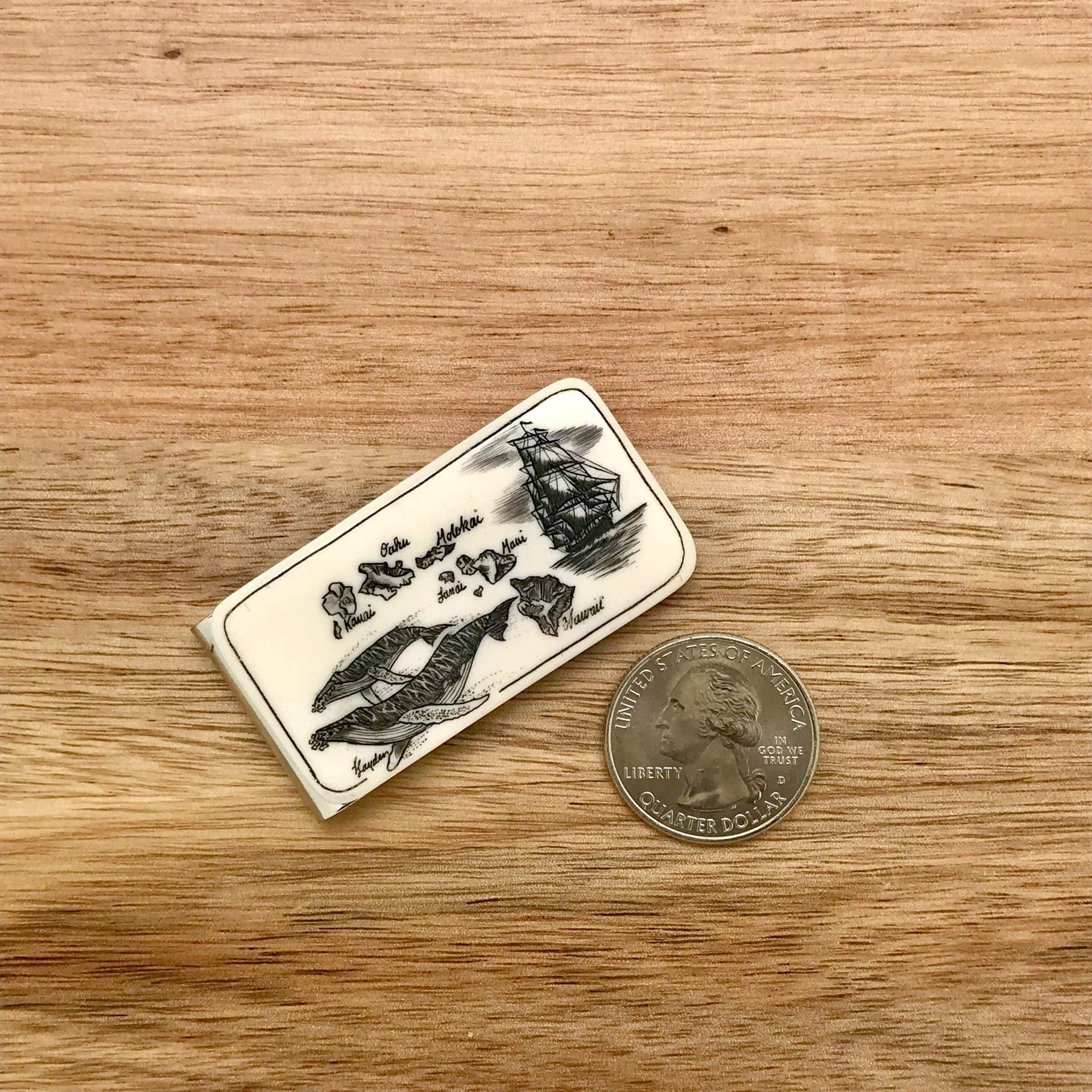 Scrimshaw Style Wide Money Clip featuring humpback whale, Hawaiian islands and ship detail designed by artist Linda Layden with US quarter for size comparison