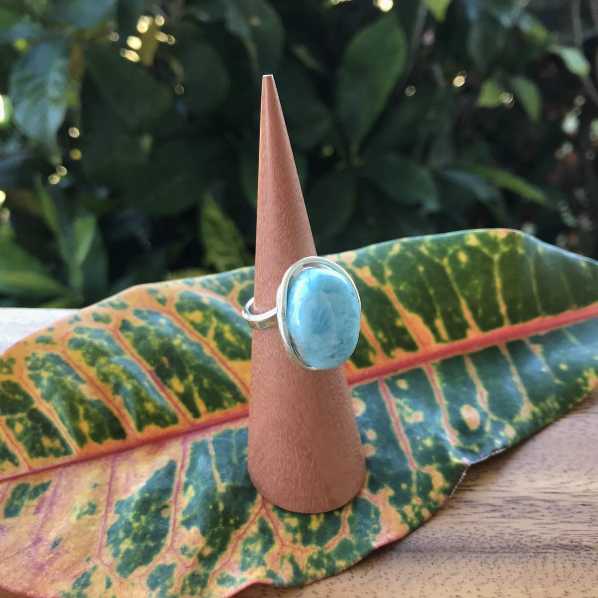 Dreamy Larimar Sterling Silver Adjustable Ring on ring cone holder on top of colorful leaf