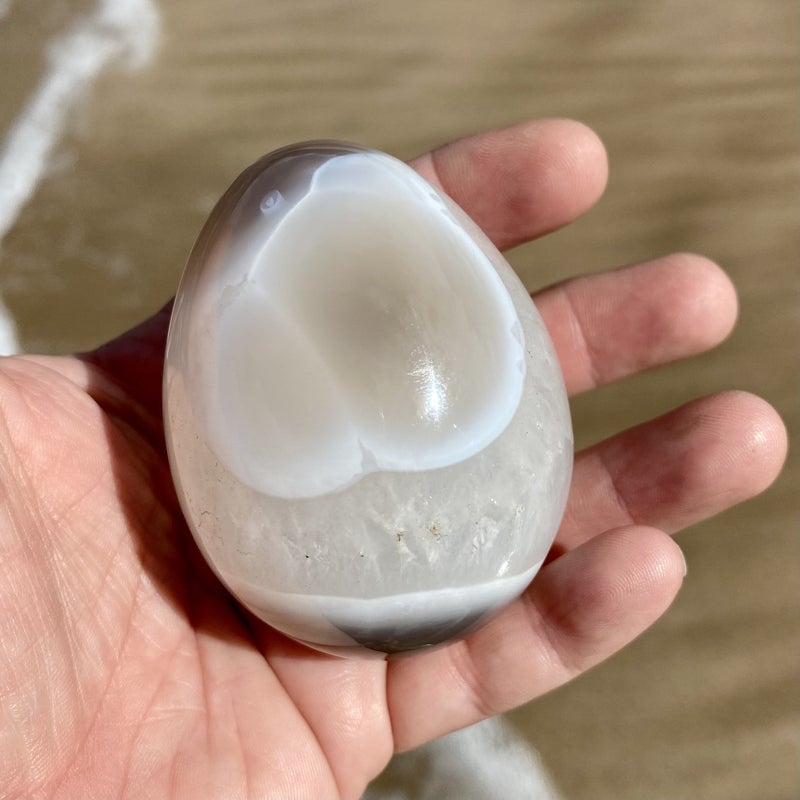 person holding banded agate egg in palm