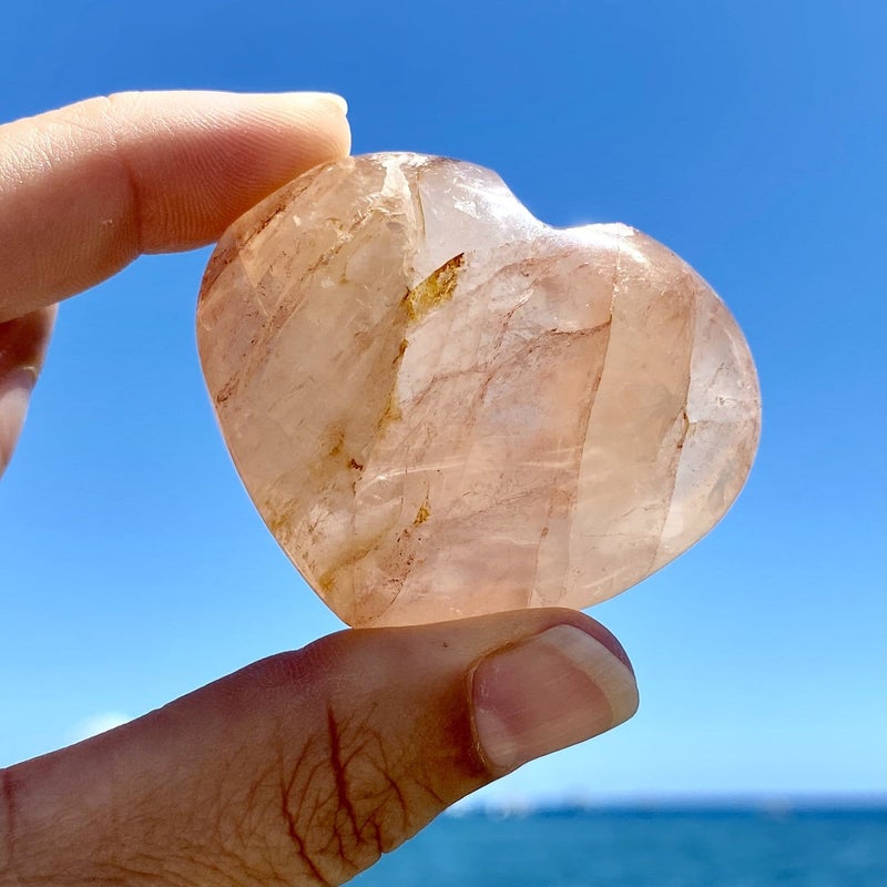 person holding up hematoid quartz heart stone