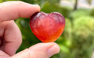 Person holding a single carnelian heart stone