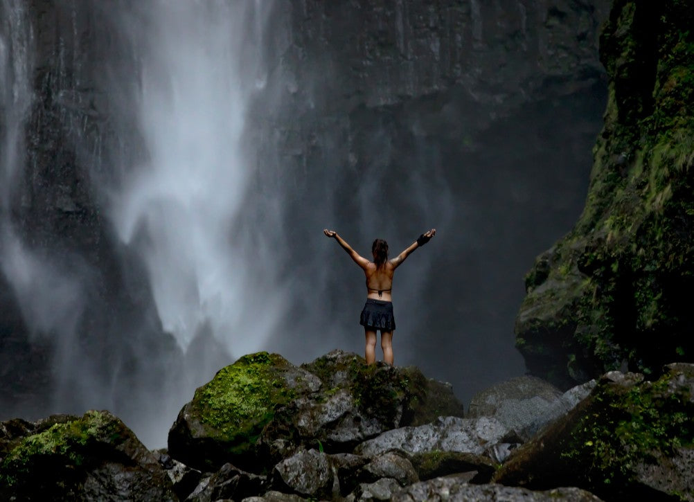 Lady standing in front of waterfall coming from black stone