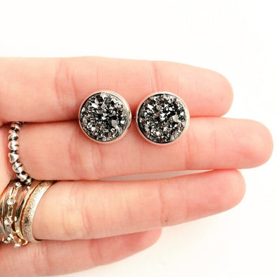 Two earring studs in a woman's fingers
