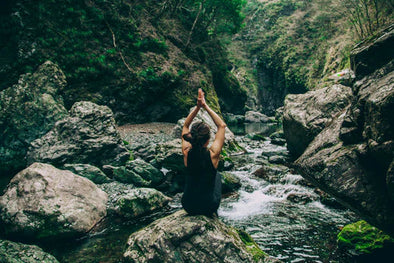 woman meditating by a stream